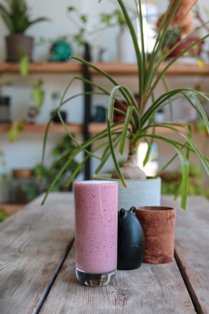 Un verre de smoothie devant des plantes - That girl