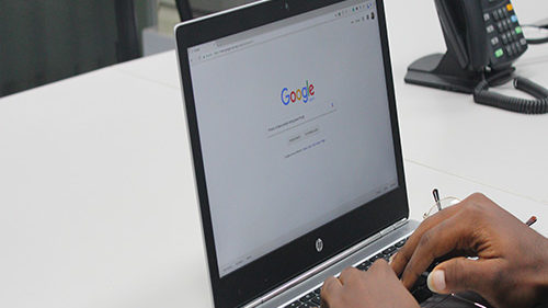 personne qui tape sur la barre de recherche google